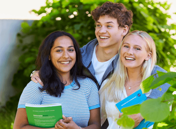 Tre leende gymnasieungdomar i grönska